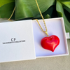Red heart-shaped pendant on a gold chain in a box with 'The Christy F Collection' branding.