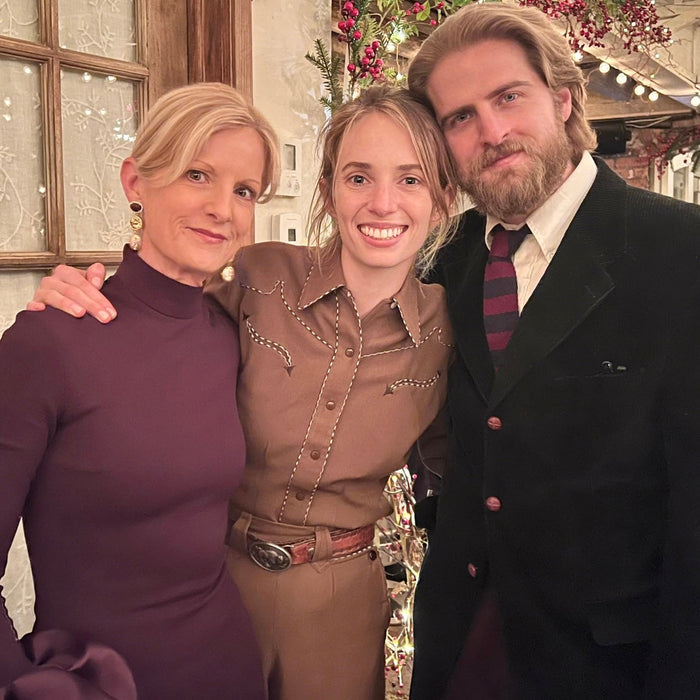 Three people posing together in a festive indoor setting with Christmas decorations.