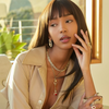 Woman in beige outfit with jewelry sitting outdoors