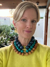Woman wearing a colorful beaded necklace outdoors with plants in the background