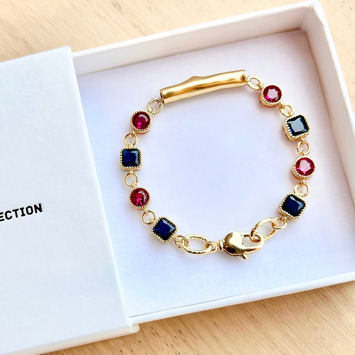 Gold bracelet with colorful gemstones in a white box labeled 'YF Collection'.