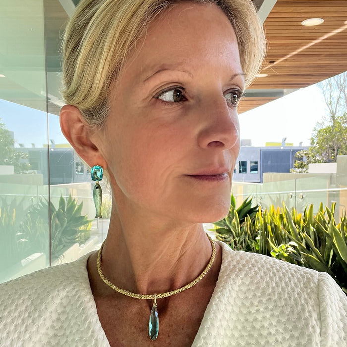 Woman wearing a white textured garment with a necklace, standing outdoors.