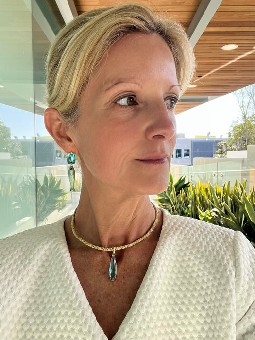 Woman wearing a white textured garment with a necklace, standing outdoors.