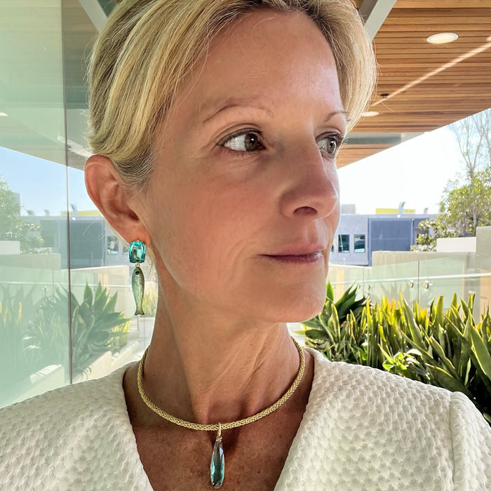 Woman wearing a white textured garment with a necklace, standing outdoors.