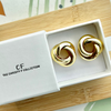 Gold earrings in a box with 'The Christy F Collection' branding.
