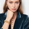 Woman wearing gold jewelry including a necklace, bracelet, and earrings on a white background