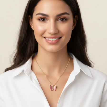 Woman wearing a gold necklace with a butterfly pendant against a beige background