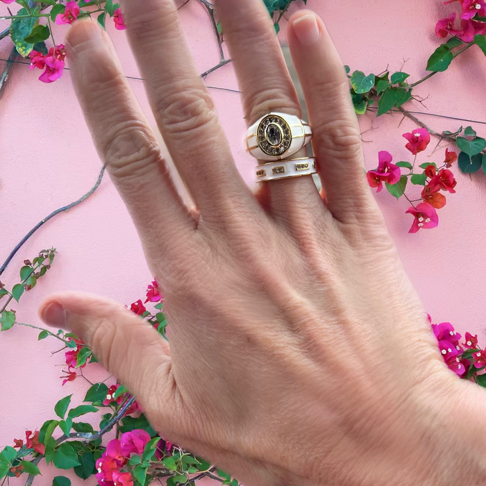 Hand wearing a ring with a pink floral background
