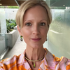Woman wearing a colorful patterned blouse with a blurred outdoor background