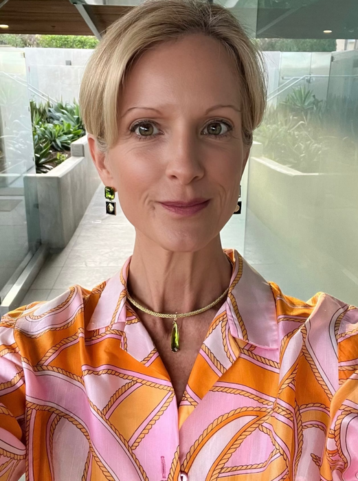 Woman wearing a colorful patterned blouse with a blurred outdoor background