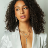 A woman wearing a gold-filled bling necklace with a green eye charm and a gold-filled paperclip chain.