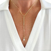 Gold necklace with a pendant on a person wearing a white shirt.