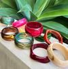 Colorful bangles on a stone surface with green plants in the background