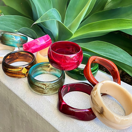 Colorful bangles on a stone surface with green plants in the background