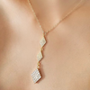 Gold necklace with diamond-shaped pendant on a person's neck