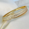 A gold-filled bracelet adorned with shimmering cz micro pave crystals, displayed on a white fabric surface.