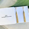 Gold earrings in a 'The Christy F Collection' box with green leaves in the background