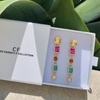 Colorful earrings in a Christy F Collection box with green leaves in the background