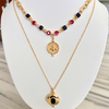 A gold-filled necklace with sapphire and ruby gemstones, featuring a locket pendant with a queen bee motif, displayed on a mannequin.