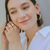 Woman wearing gold jewelry including earrings and a necklace.
