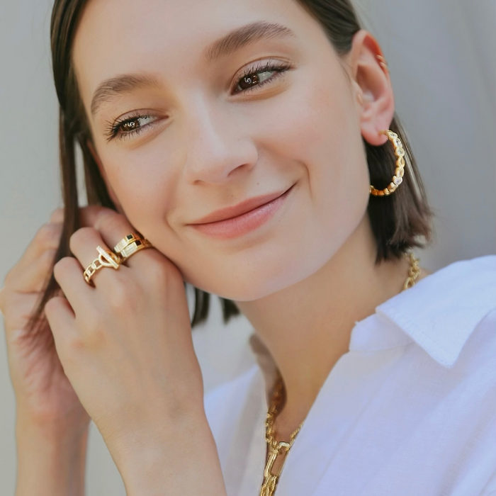 Woman wearing gold jewelry including earrings and a necklace.