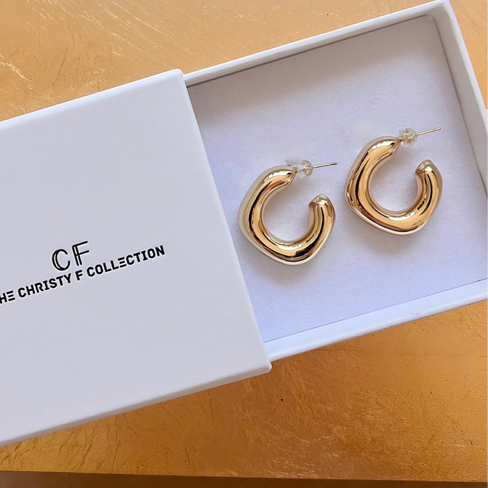 Gold hoop earrings in a white box with 'The Christy F Collection' branding.