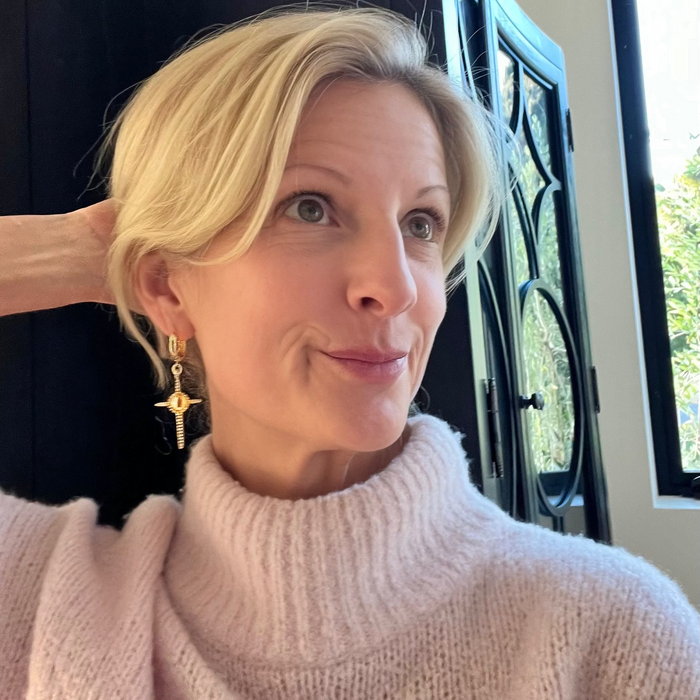 Woman with blonde hair wearing a light pink sweater indoors.