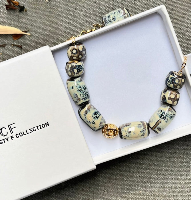 Beaded bracelet with decorative beads on a white box, featuring the 'Fusty F Collection' branding.
