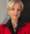 Woman wearing a red coat with a black collar against a neutral background