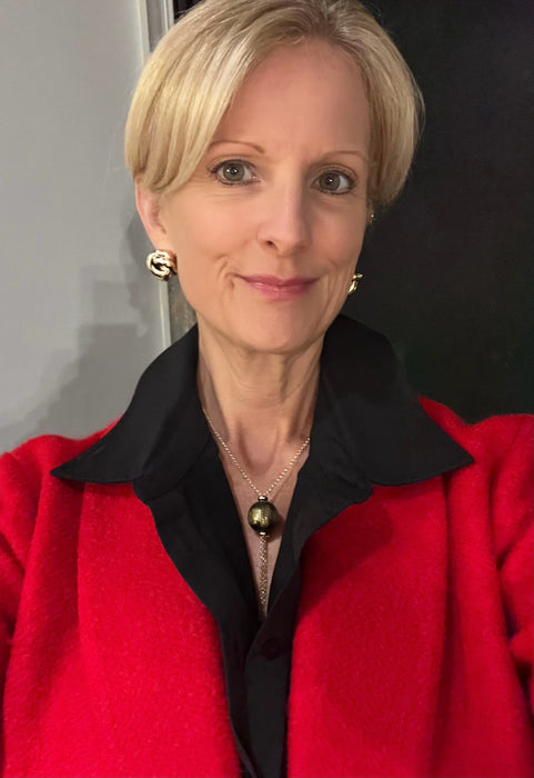 Woman wearing a red coat with a black collar against a neutral background
