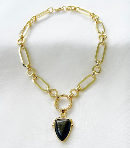 A black shield-shaped pendant on a gold-filled chain choker necklace.