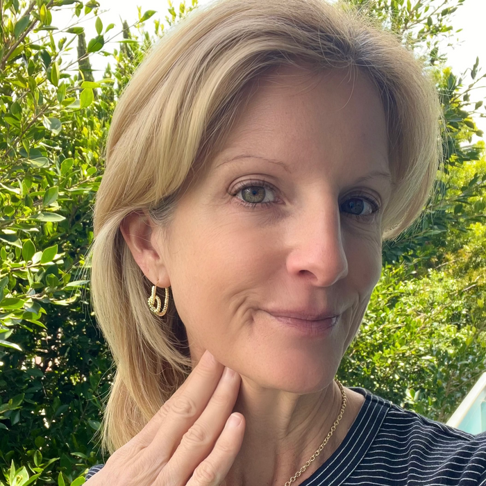 Woman wearing earrings with a green leafy background
