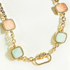 Gold necklace with square gemstones on a white background