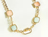 Gold necklace with square gemstones on a white background