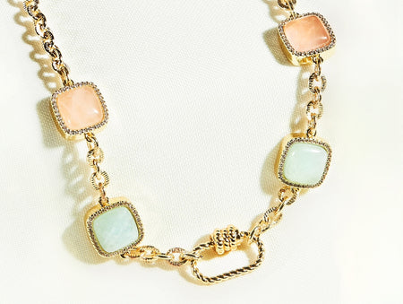 Gold necklace with square gemstones on a white background