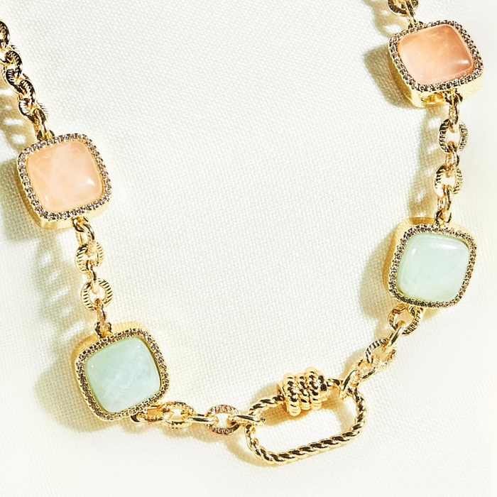 Gold necklace with square gemstones on a white background
