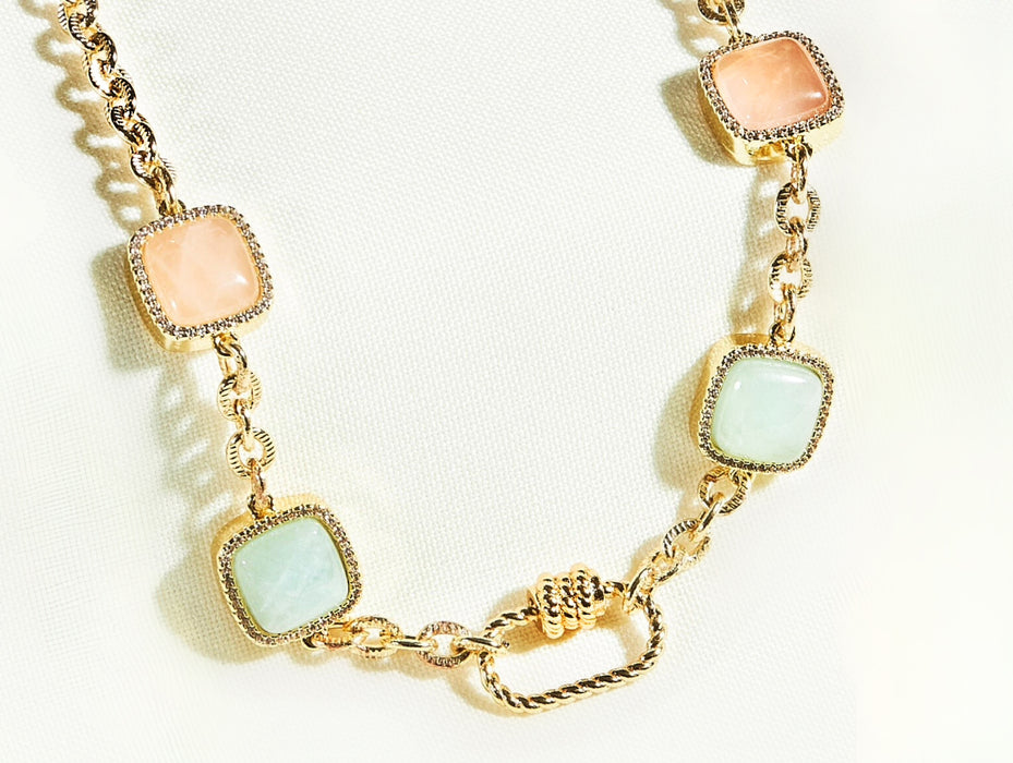 Gold necklace with square gemstones on a white background