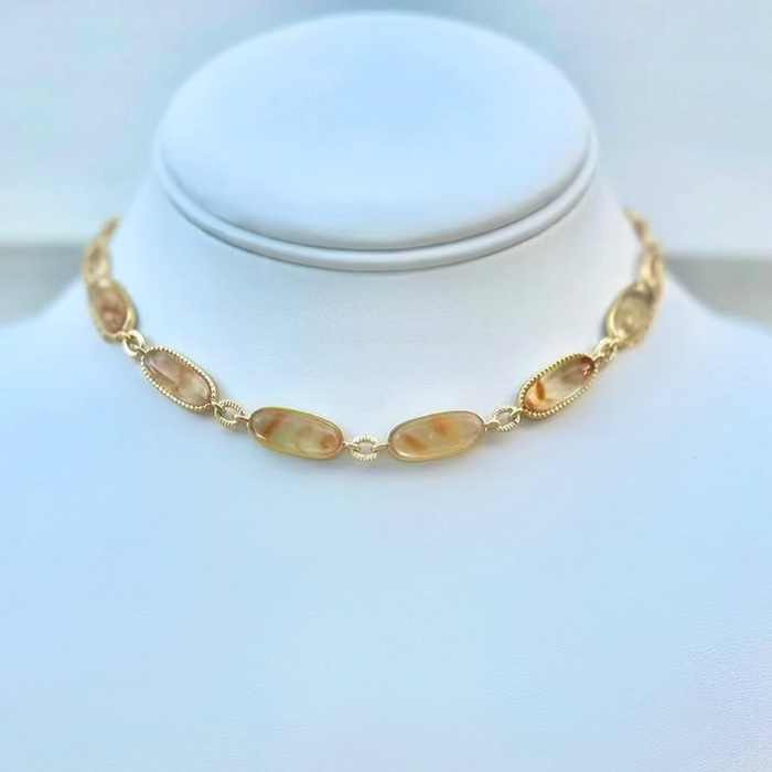 A gold-filled rope style choker necklace with citrine gemstone connectors displayed on a white mannequin neck.