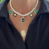 Necklace with pearls and decorative pendants on a person wearing a black shirt.