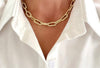 Gold chain necklace worn by a person wearing a white shirt.