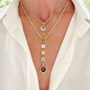 Gold necklace with gemstone pendants on a white shirt