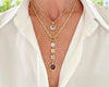 Gold necklace with gemstone pendants on a white shirt
