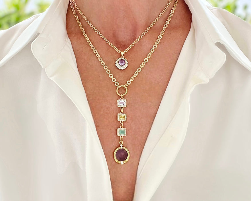 Gold necklace with gemstone pendants on a white shirt