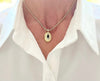 Gold necklace with a pendant worn by a person in a white shirt.