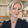 Woman wearing a black outfit with a gold necklace and earrings indoors.