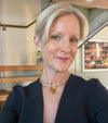 Woman wearing a black outfit with a gold necklace and earrings indoors.