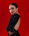 Woman wearing a black dress with cut-out design on a red background