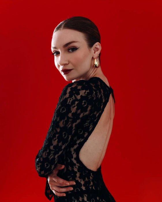 Woman wearing a black dress with cut-out design on a red background