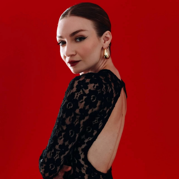 Woman wearing a black dress with cut-out design on a red background