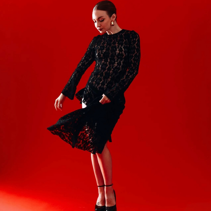 Woman in a black lace dress on a red background